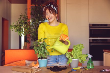 Téléchargez les photos : Home gardening. Woman in yellow planting and watering home plants - en image libre de droit