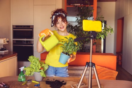 Téléchargez les photos : Home gardening. Woman in yellow planting and watering home plants - en image libre de droit