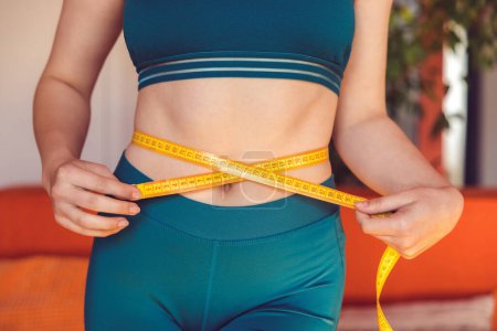 Téléchargez les photos : Lose weight. Close up of a woman measuring her waist - en image libre de droit