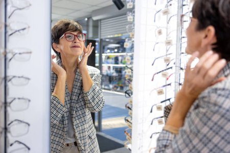 Photo for Optical store. Mid aged good-looking lady trying on eyeglasses at the optical store - Royalty Free Image