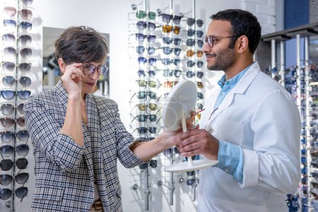 Photo for New eyeglasses. Male optometrist helpting a woman to choose eyeglasses - Royalty Free Image