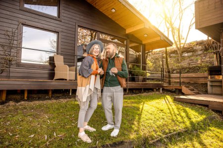 Photo for New home. Happy man and woman standing near their new house and smiling - Royalty Free Image