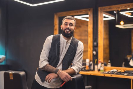 Stylish barber. Dark-haired bearded man in a stylish outfit