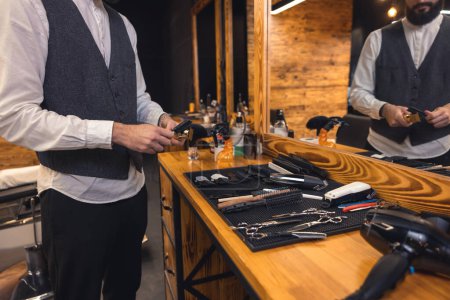 Téléchargez les photos : Barber at work. Barber with hairdressing tools an the barbershop - en image libre de droit