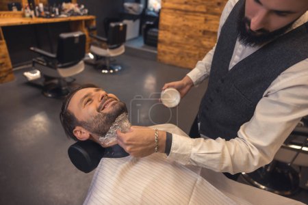 Photo for Preparing for shaving. Barber applying foam on the clients neck before shaving - Royalty Free Image