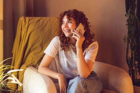 Photo for On the call. Curly-haired ginger girl talking on the phone - Royalty Free Image