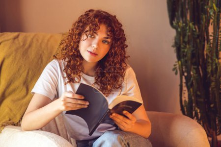 Téléchargez les photos : Reading. Ginger curly-haired girl reading a book - en image libre de droit