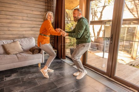 Foto de Active couple. Happy couple dancing at home and looking energized and excited - Imagen libre de derechos