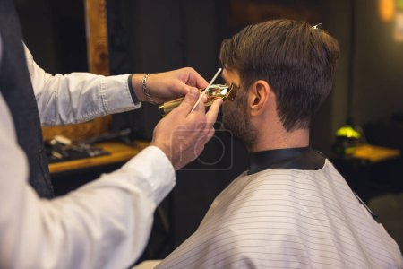 Foto de Beard trimming. Barber carefully trimming the clients beard - Imagen libre de derechos