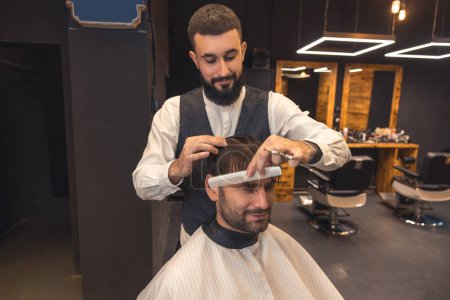 Photo for New haircut. Hairdresser making a new haircut to the male client - Royalty Free Image