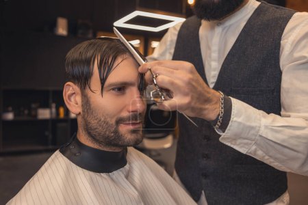 Foto de New haircut. Hairdresser making a new haircut to the male client - Imagen libre de derechos
