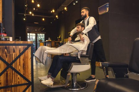 Foto de At the hairdresser. Professional male hairdresser working with the client - Imagen libre de derechos