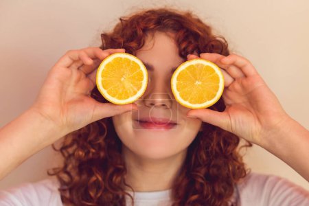 Téléchargez les photos : Love citrus. Curly-haired ginger girl with slices of orange in hands - en image libre de droit
