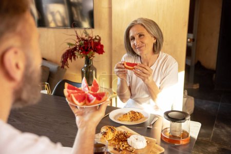 Photo for Happy couple. Mature couple peacefully having breakfast and looking happy - Royalty Free Image