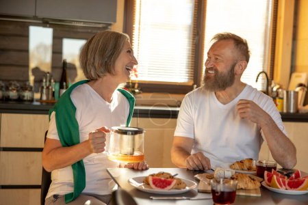 Photo for Happy couple. Mature couple peacefully having breakfast and looking happy - Royalty Free Image