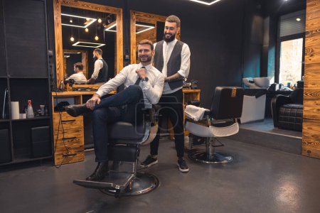 Photo for At the barbers. Elegant client sitting in a chiar in the barbershop - Royalty Free Image
