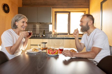 Photo for Breakfast together. Man and woman having breakfast together and looking contented - Royalty Free Image