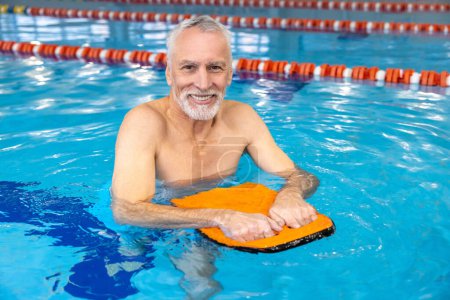 Téléchargez les photos : In the swimming pool. Smiling senior gray-haired man swimming - en image libre de droit