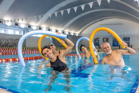 Téléchargez les photos : Water aerobics. Group of senior having an exercise with noodle floats - en image libre de droit