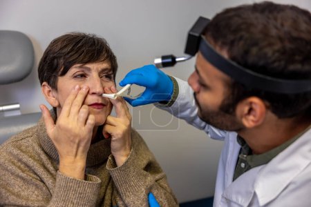 Foto de Chequeo nasal. Mujer mayor que se somete a control auditivo en ent doctor - Imagen libre de derechos