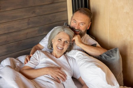 Foto de Closeness. Mature couple staying in bed and feeling close and relaxed - Imagen libre de derechos