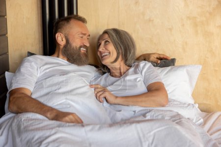 Téléchargez les photos : Joyeux couple. Couple d'âge mûr restant au lit et regardant heureux - en image libre de droit