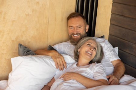 Téléchargez les photos : Joyeux couple. Couple d'âge mûr restant au lit et regardant heureux - en image libre de droit