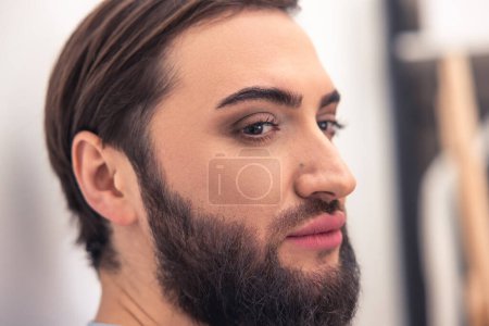 Téléchargez les photos : Gros plan portrait d'un gars attrayant avec un maquillage naturel sur son visage réfléchissant sur quelque chose - en image libre de droit