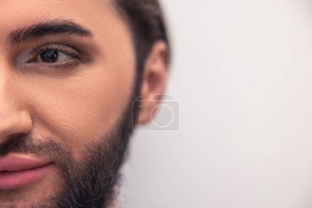 Foto de Closeup portrait of a pensive bearded dark-haired male person wearing natural makeup on the face - Imagen libre de derechos