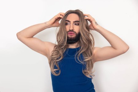 Téléchargez les photos : Waist-up portrait of a calm confident young transgender person adjusting the wig on the head - en image libre de droit