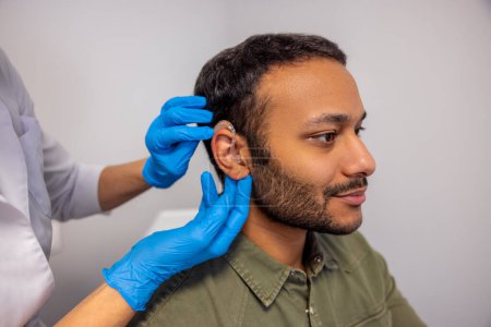 Photo for Hearing aid. ENT doctor implementing hearing aid to the patients ear - Royalty Free Image