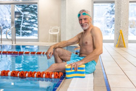 Téléchargez les photos : Senior swimmer. Senior swimmer in watersports goggles at the swimming pool - en image libre de droit