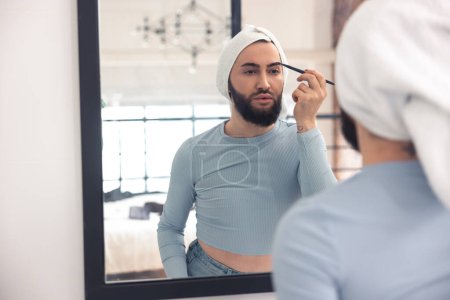 Photo for Focused male person coloring his eyebrows with the black pencil before the mirror - Royalty Free Image