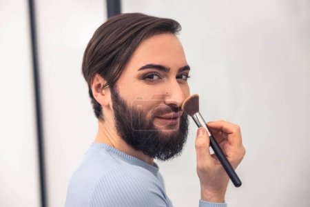 Photo for Portrait of a cute guy posing for the camera while powdering the tip of his nose - Royalty Free Image