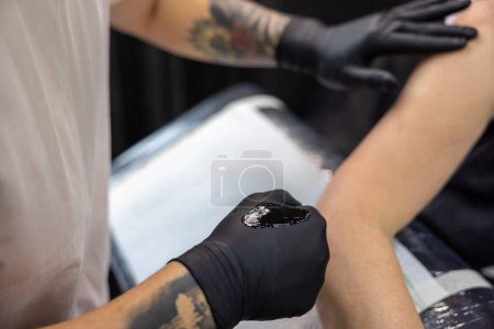 Téléchargez les photos : Dans le salon de tatouage. Femme aux cheveux gris se faisant tatouer dans le salon de tatouage - en image libre de droit