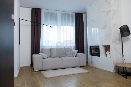 Foto de Acogedor sofá con cojines grises situado junto a un gran ventanal en la sala de estar - Imagen libre de derechos
