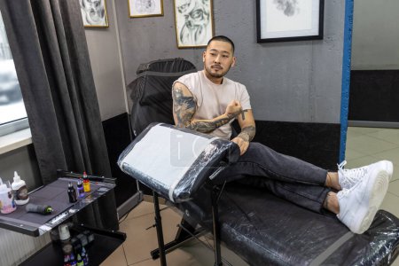 Téléchargez les photos : Un amateur de tatouage. Jeune homme asiatique avec de gros tatouages sur ses bras - en image libre de droit