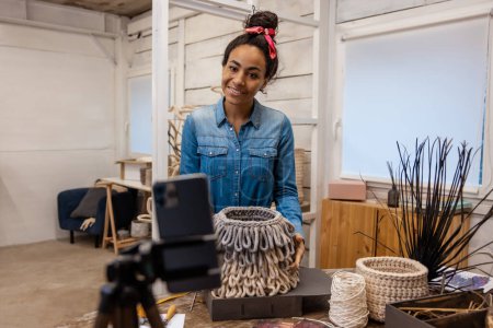 Téléchargez les photos : Atelier de tricot en ligne. Jeune femme aux cheveux bruns expliquant comment tricoter le sac - en image libre de droit