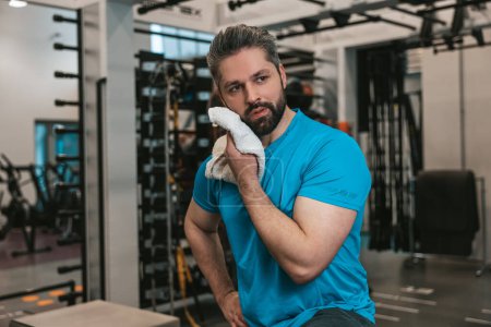 Photo for Exhausted. Young man wiping sweat with the towel after workout - Royalty Free Image