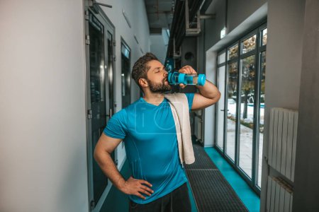 Photo for After workout. Young athlete drinking water after exhausting workout - Royalty Free Image