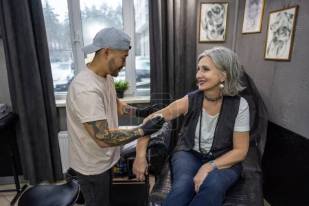 Téléchargez les photos : Dans le salon de tatouage. Maître de tatouage parlant avec le client avant la session de tatouage - en image libre de droit