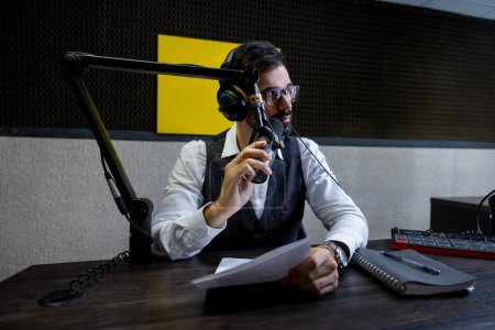 Téléchargez les photos : Radio dj. Jeune homme en headphoes assis à la table du studio - en image libre de droit