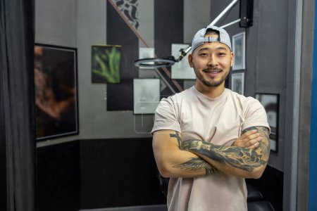 Téléchargez les photos : Maître tatoueur. Asiatique jeune homme dans un salon de tatouage - en image libre de droit