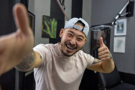Téléchargez les photos : Maître tatoueur. Asiatique jeune homme dans un salon de tatouage - en image libre de droit