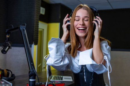 Foto de En el estudio de radio. Sonriente jovencita escuchando música - Imagen libre de derechos