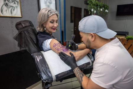 Téléchargez les photos : Dans le salon de tatouage. Tatouage maître dessin tatouage sur bras de femme - en image libre de droit
