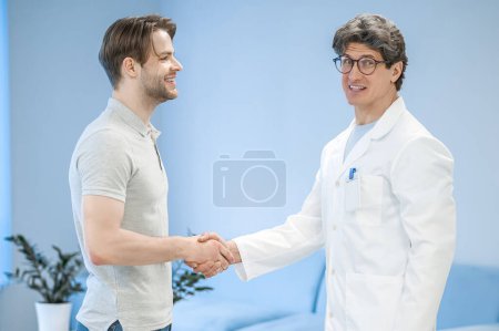 Foto de Doctor y paciente. Doctor saludando a un paciente y que se ven contentos - Imagen libre de derechos