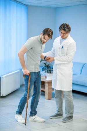 Photo for Recovery. Nurse assisting a patient to walk with a stick - Royalty Free Image