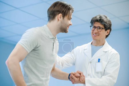 Photo for Support. Male doctor holding his patients hand and supporting him - Royalty Free Image