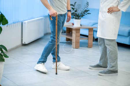 Photo for At the clinic. Patient with a stick walking to the doctor - Royalty Free Image